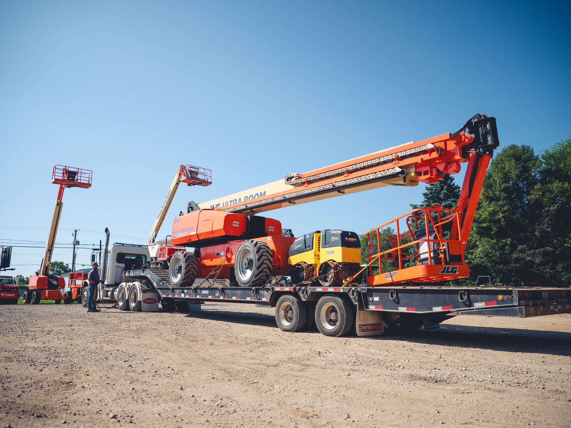 A truck is carrying a crane on a flatbed trailer.