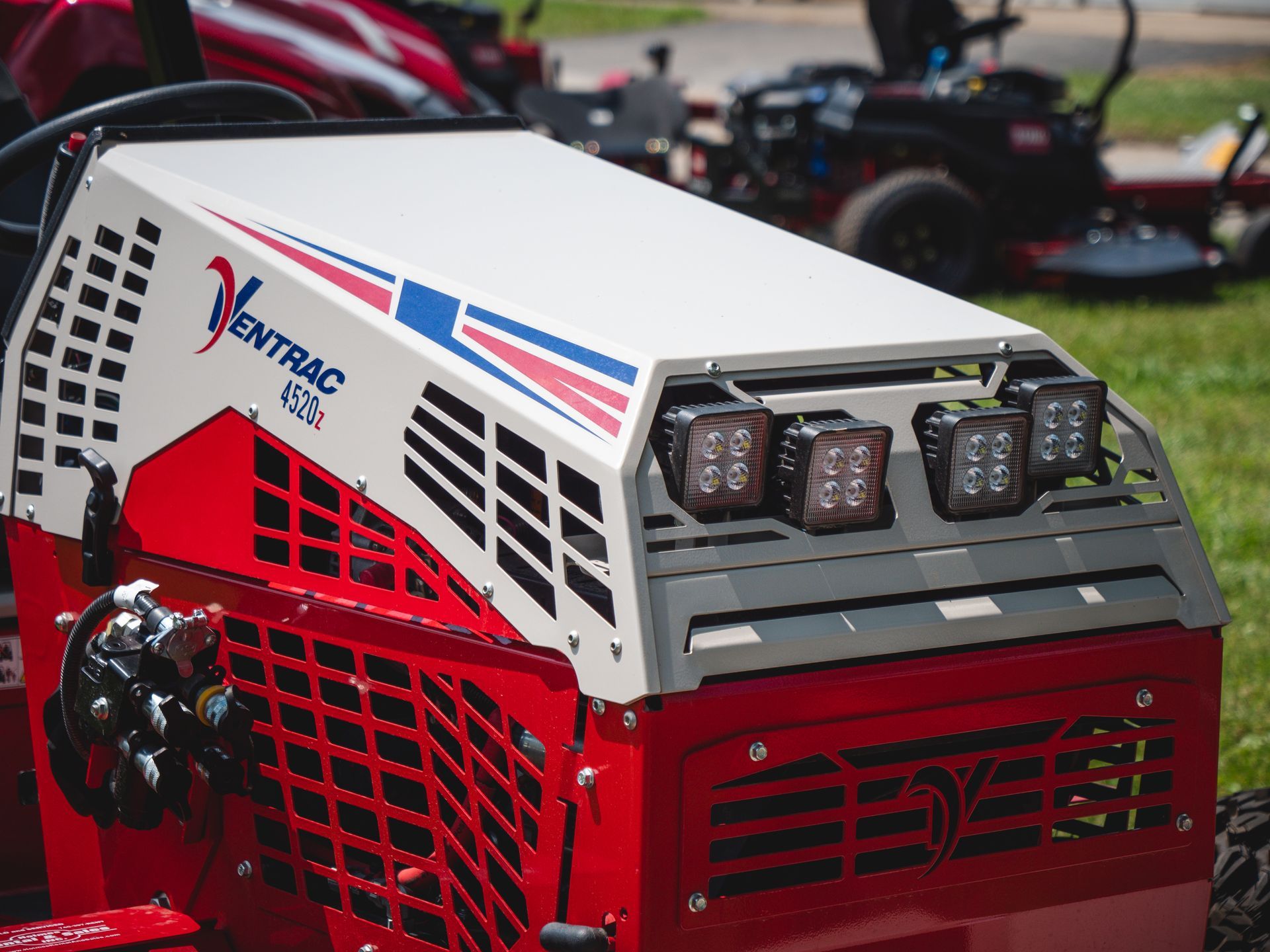 A red and white tractor is parked in the grass.