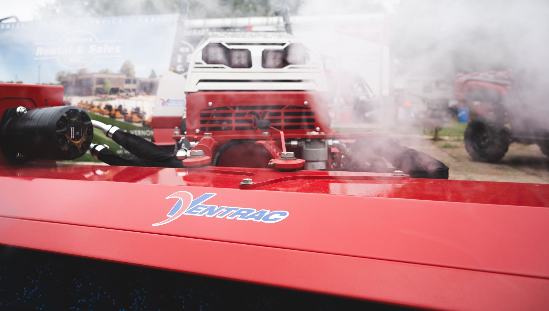 A red tractor with smoke coming out of the exhaust pipe.