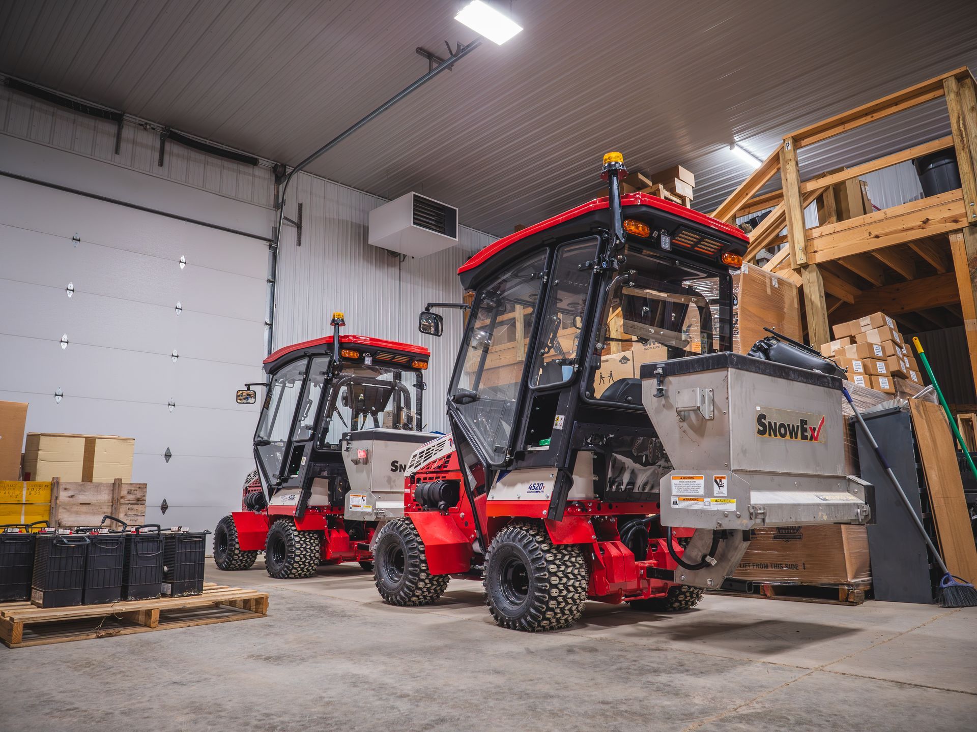 Two tractors are parked in a warehouse next to each other.