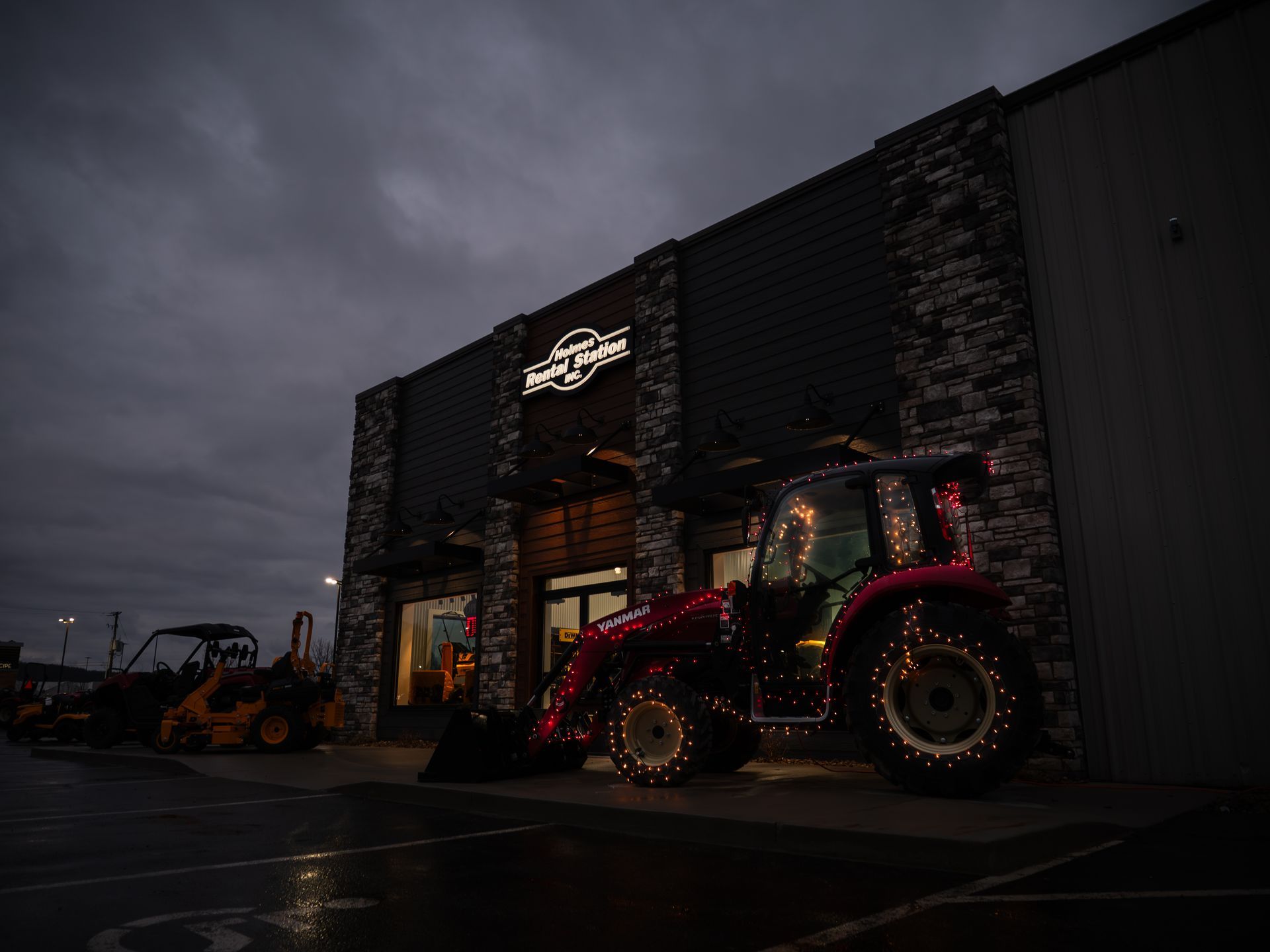 A red tractor is parked in front of a building at night.