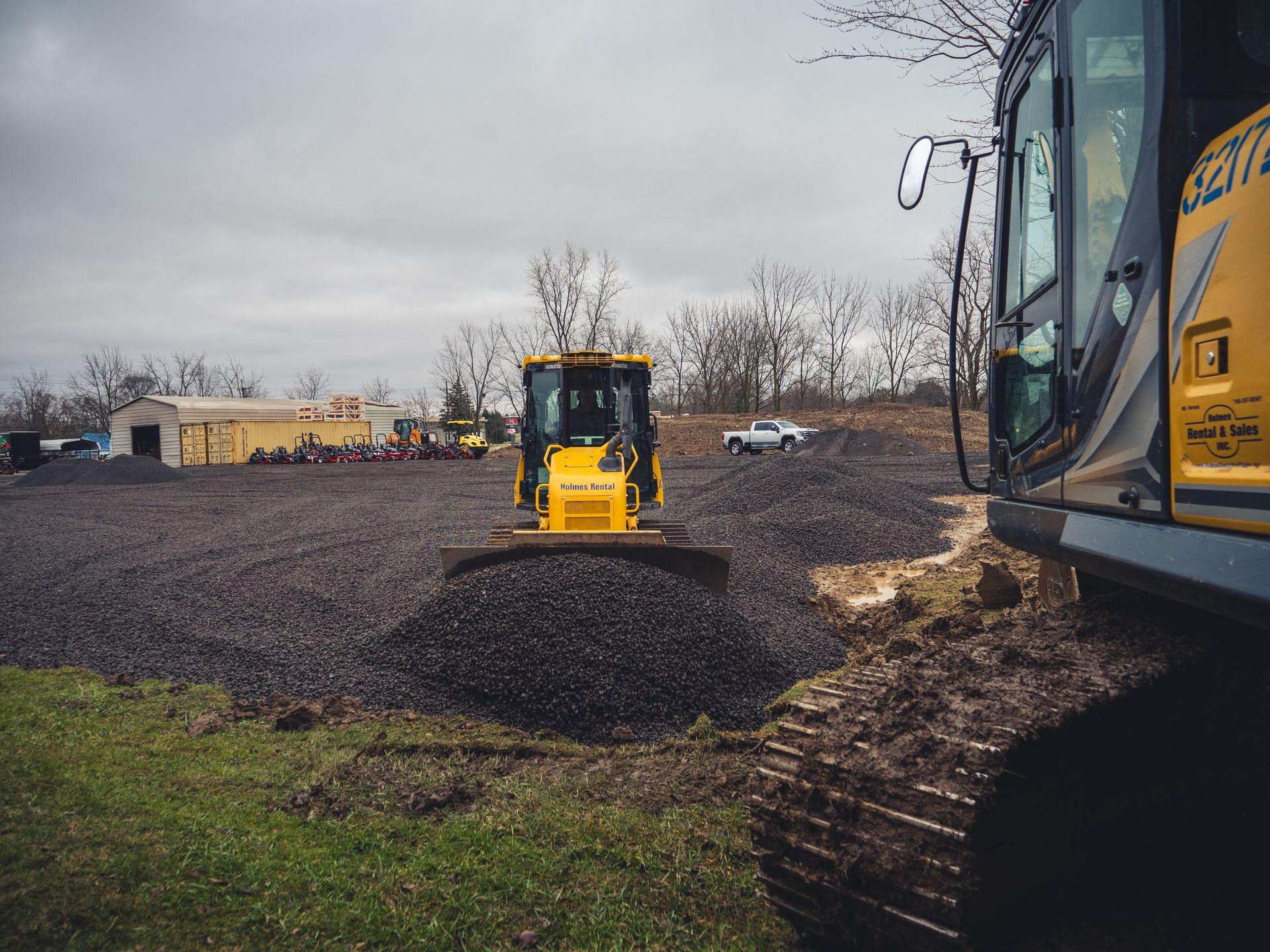 A yellow bulldozer is moving gravel in a field.