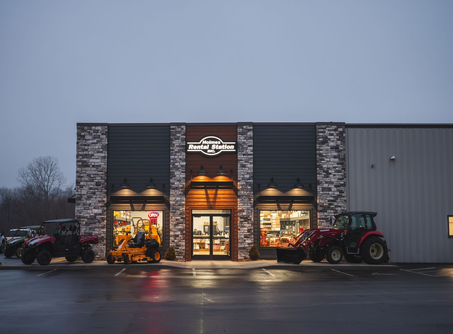 A store front with tractors parked in front of it at night.