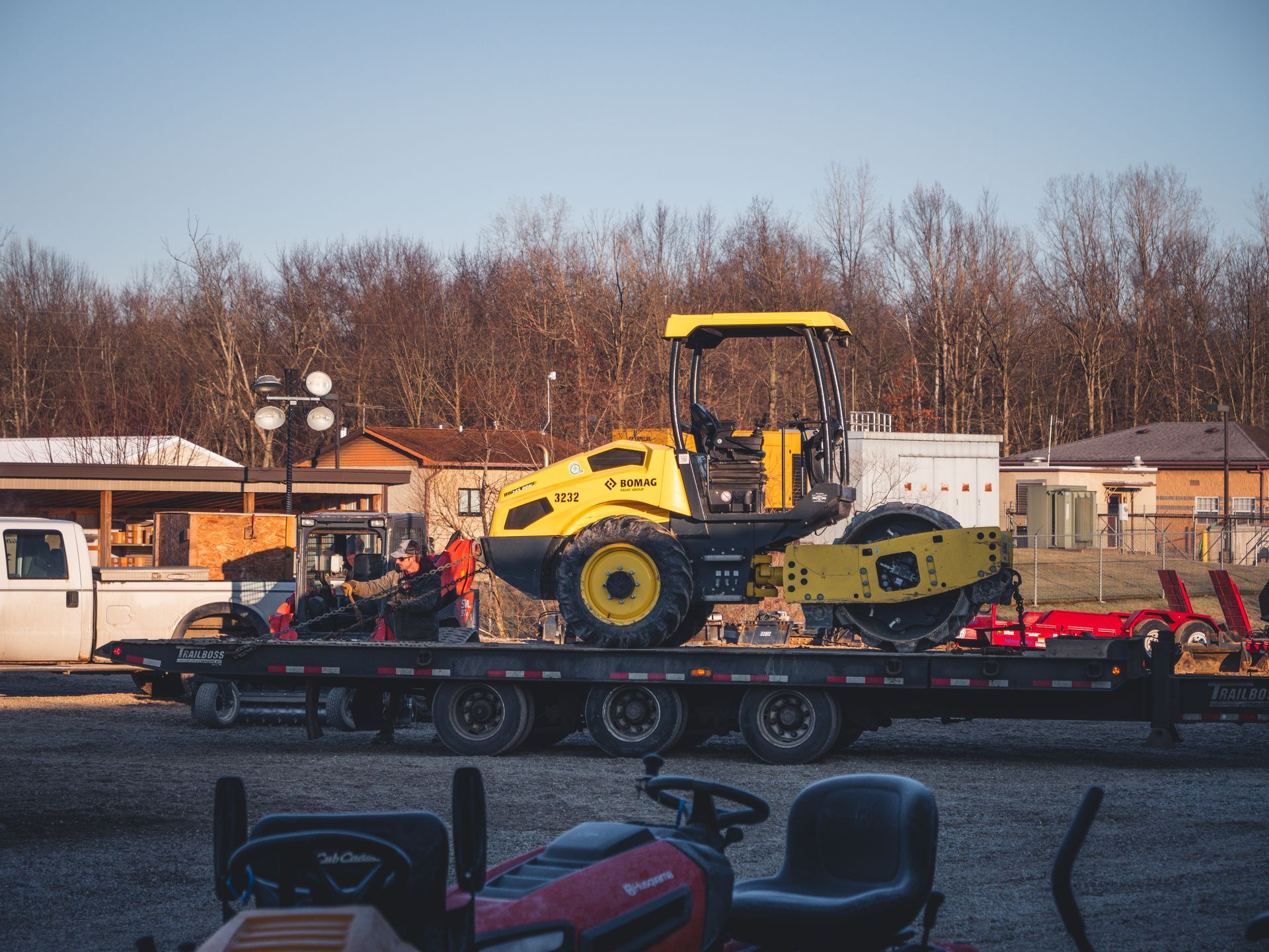 A yellow tractor is sitting on top of a trailer.