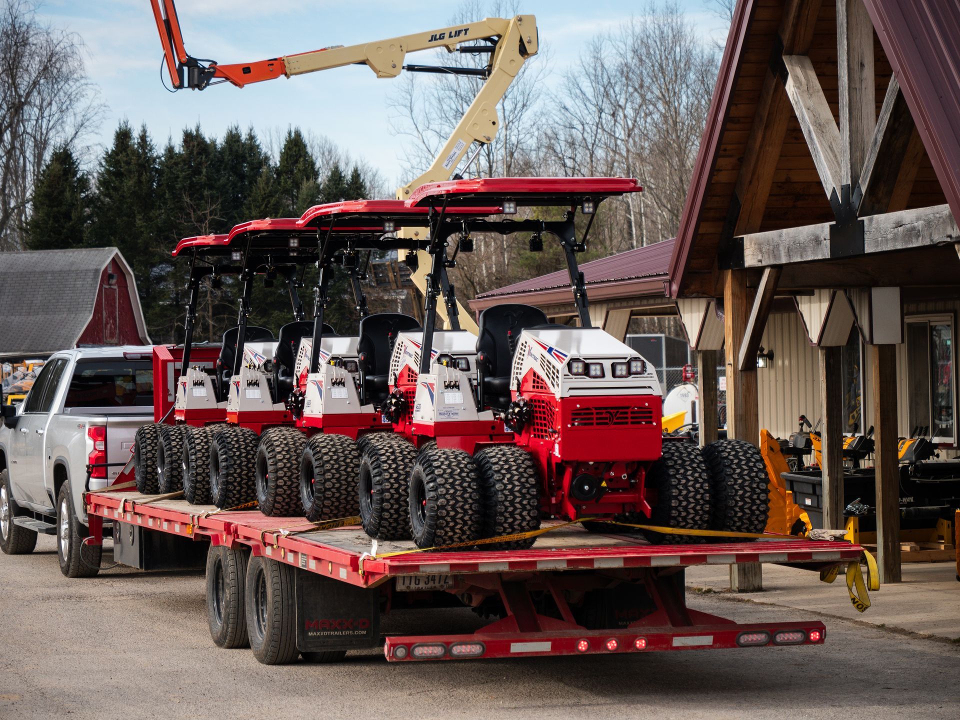 A truck is carrying a trailer with a bunch of lawn mower on it.