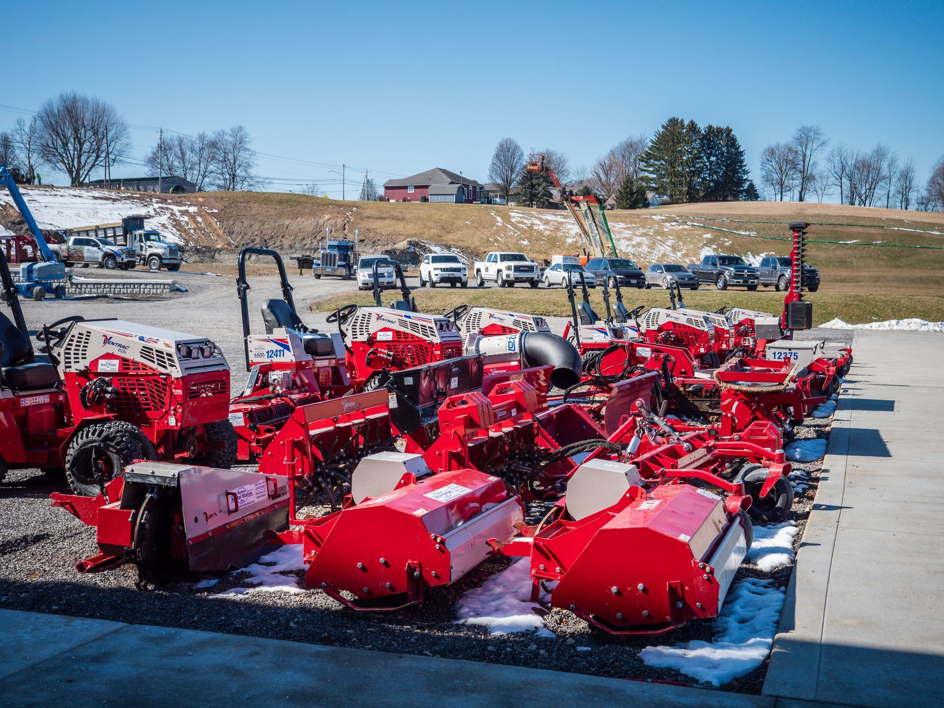 A row of red lawn mowers are parked in a parking lot.