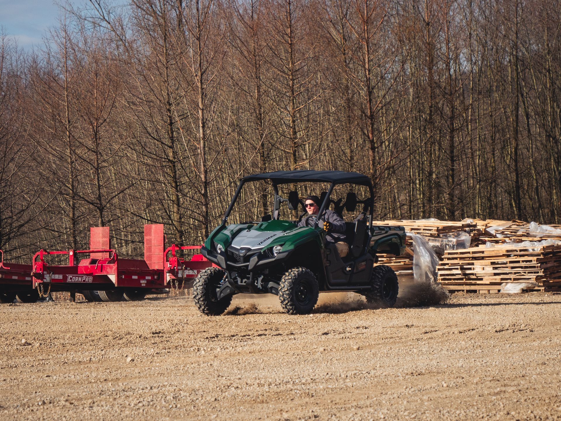 A man is driving a green atv on a dirt road.