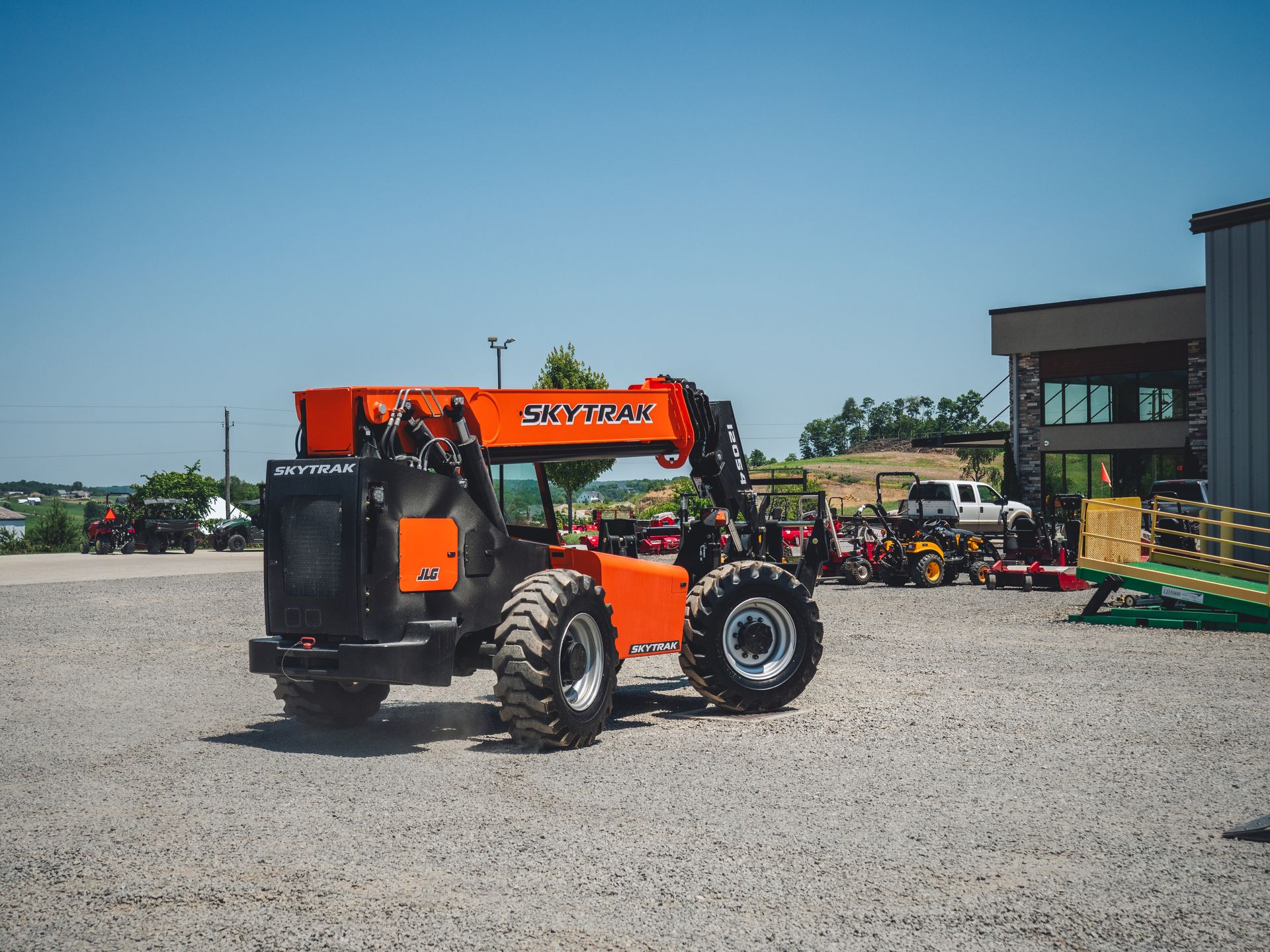 A forklift is parked in a gravel lot in front of a building.