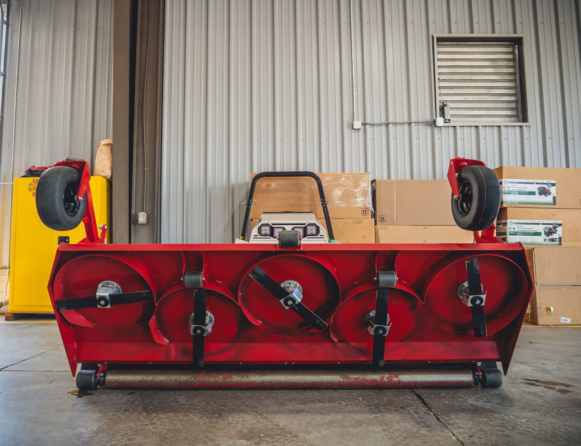 A red snow blower is sitting in a warehouse.