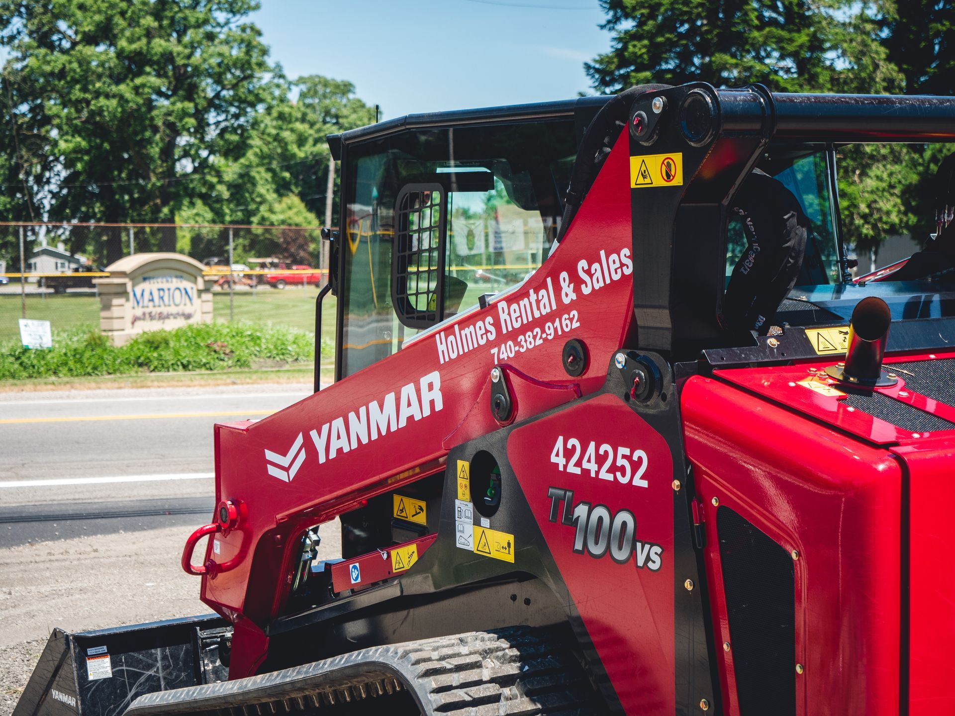 A red and black tractor is parked on the side of the road.