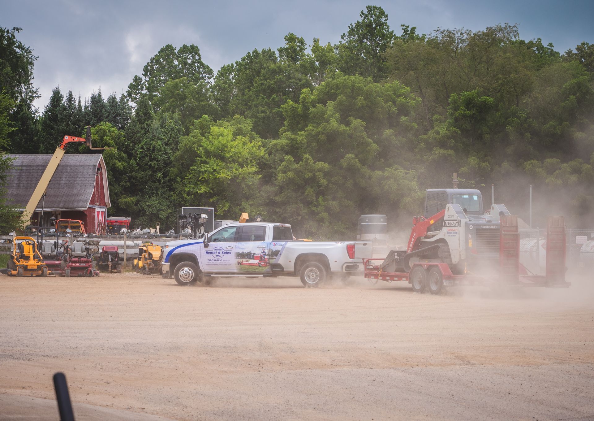 A row of trucks are parked in a dirt lot.