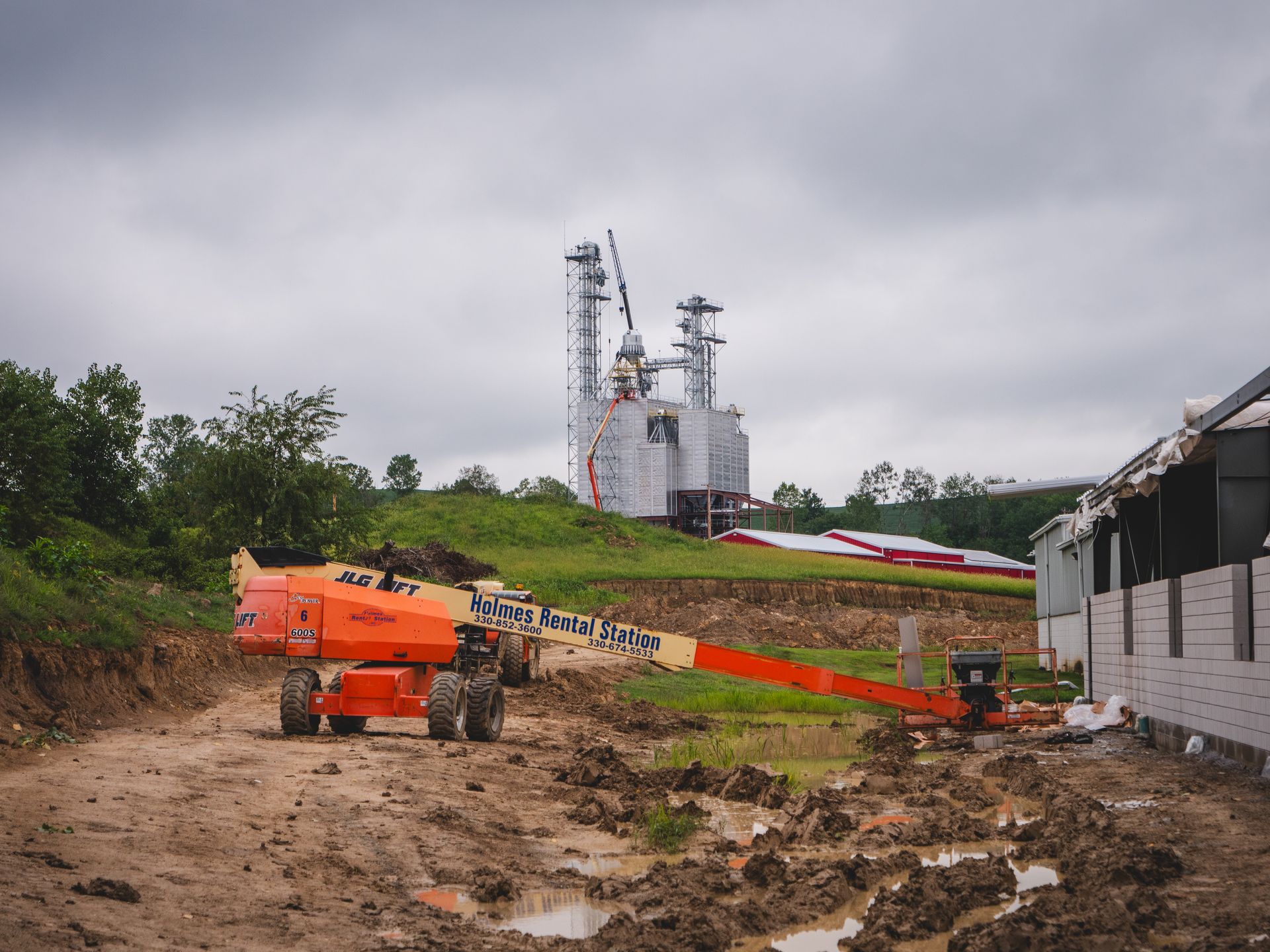 A construction site with a lot of dirt and a large building in the background.