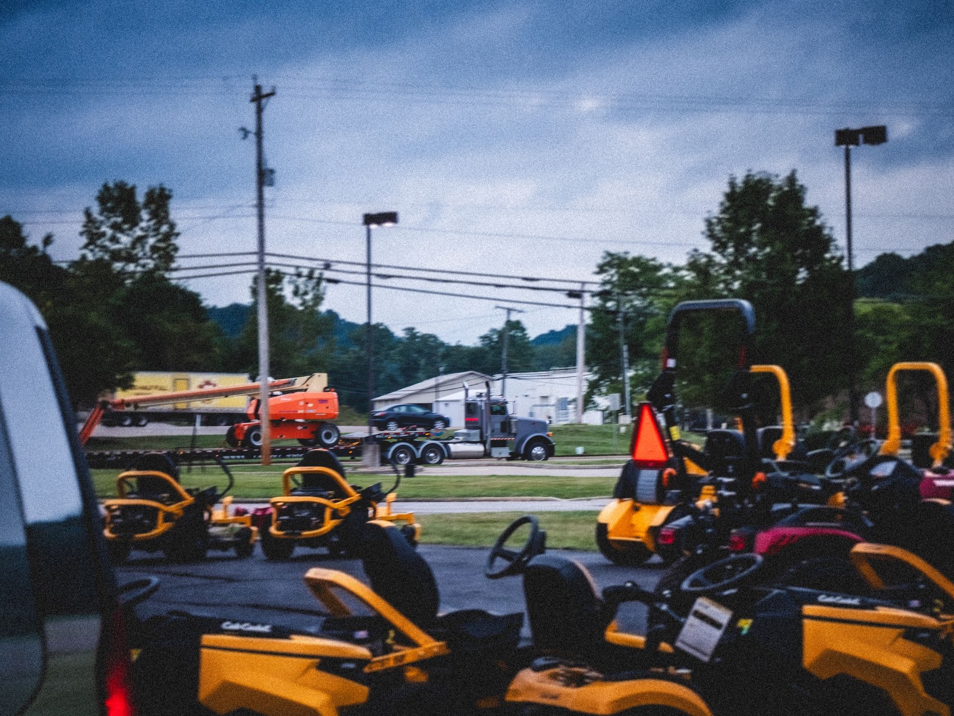 A row of yellow lawn mowers are parked in a parking lot