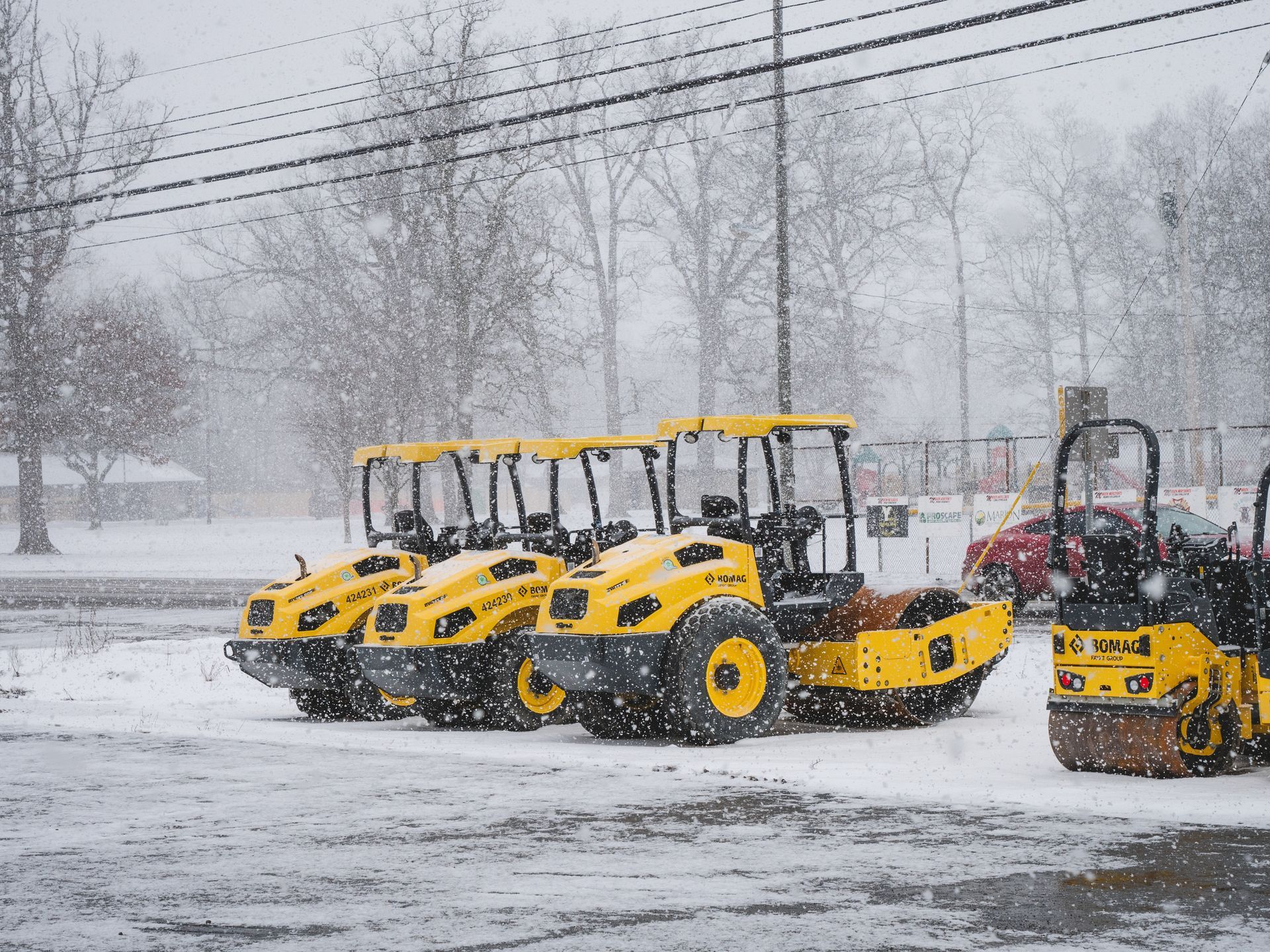 A row of yellow tractors are parked in the snow.