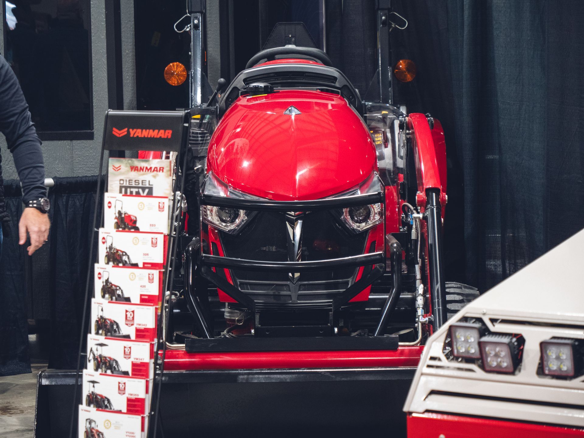 A man is standing next to a red tractor.