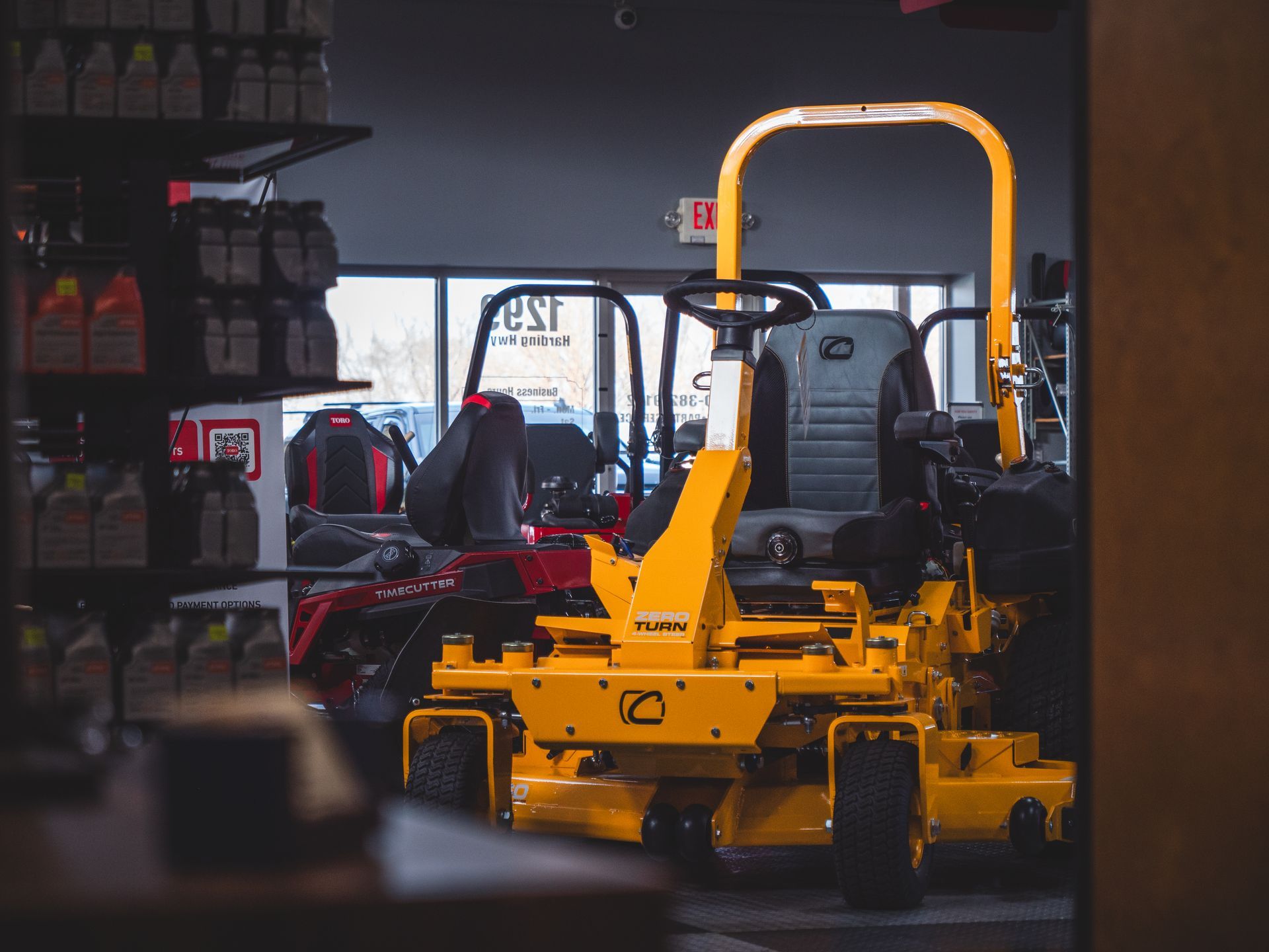 A yellow lawn mower is parked in a showroom.