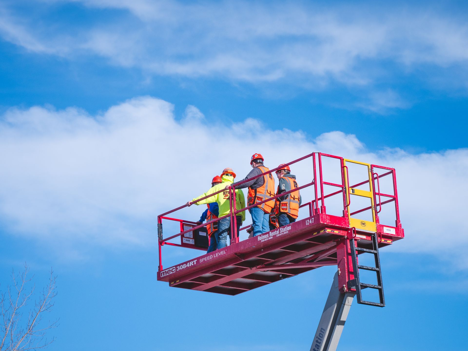 A group of construction workers are standing on a lift.