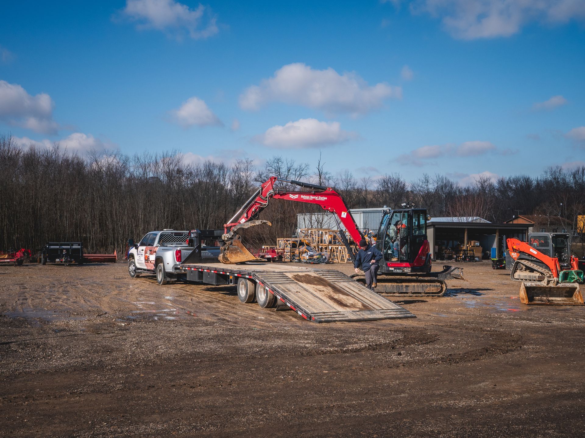 A truck is being towed by an excavator in a dirt field.