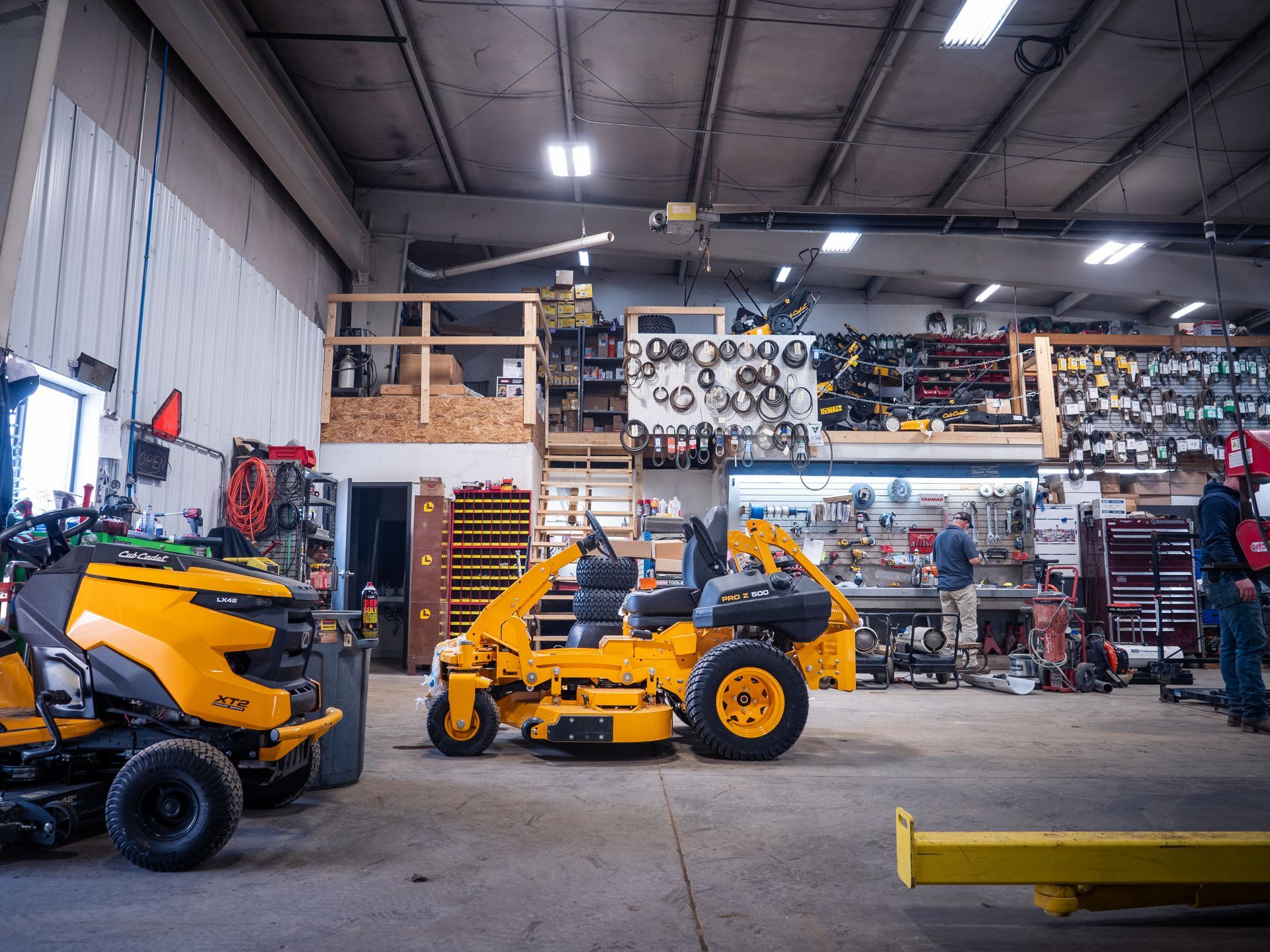 A man is working on a yellow lawn mower in a garage.
