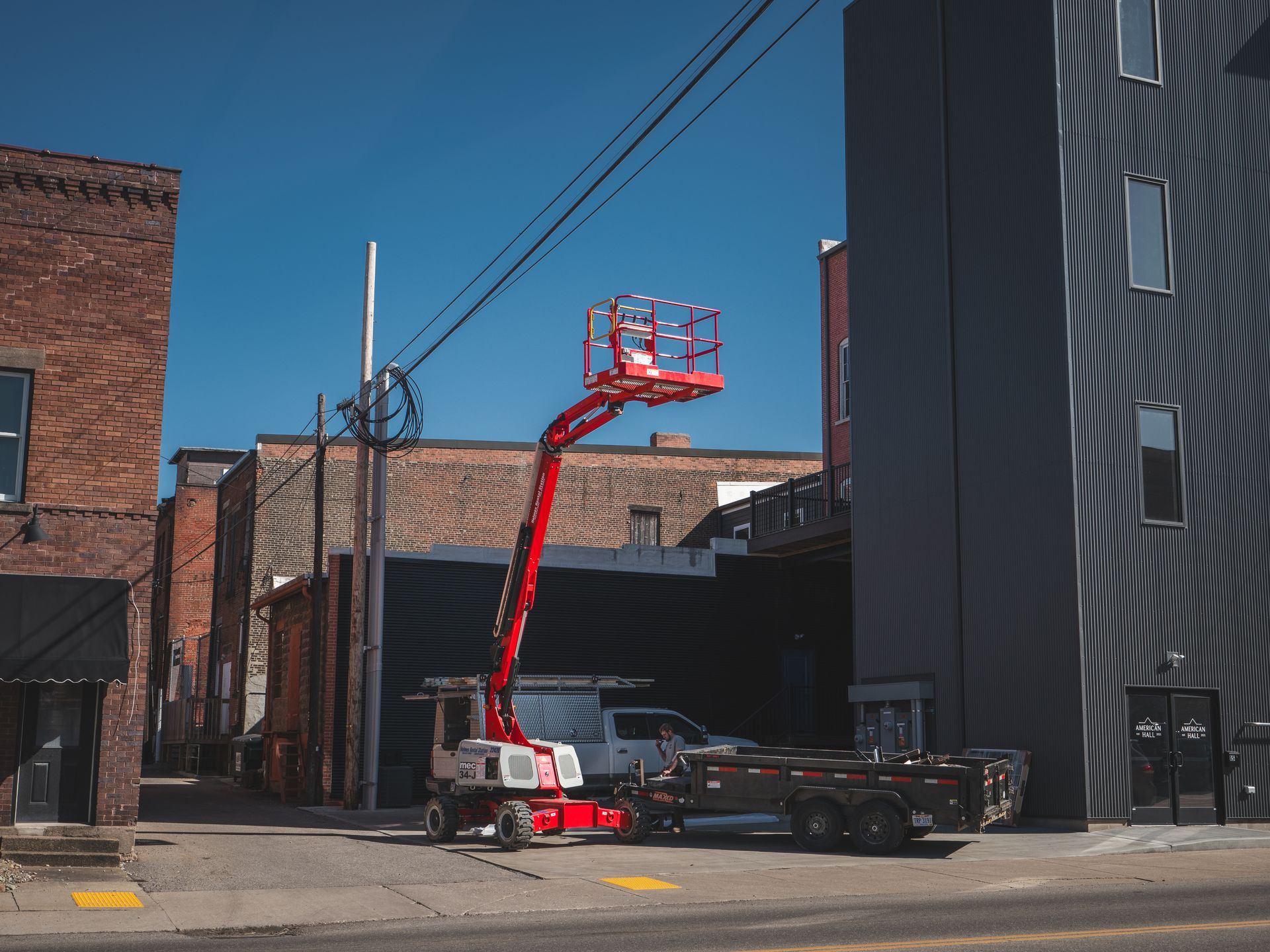 A red aerial lift is parked on the side of the road in front of a building.