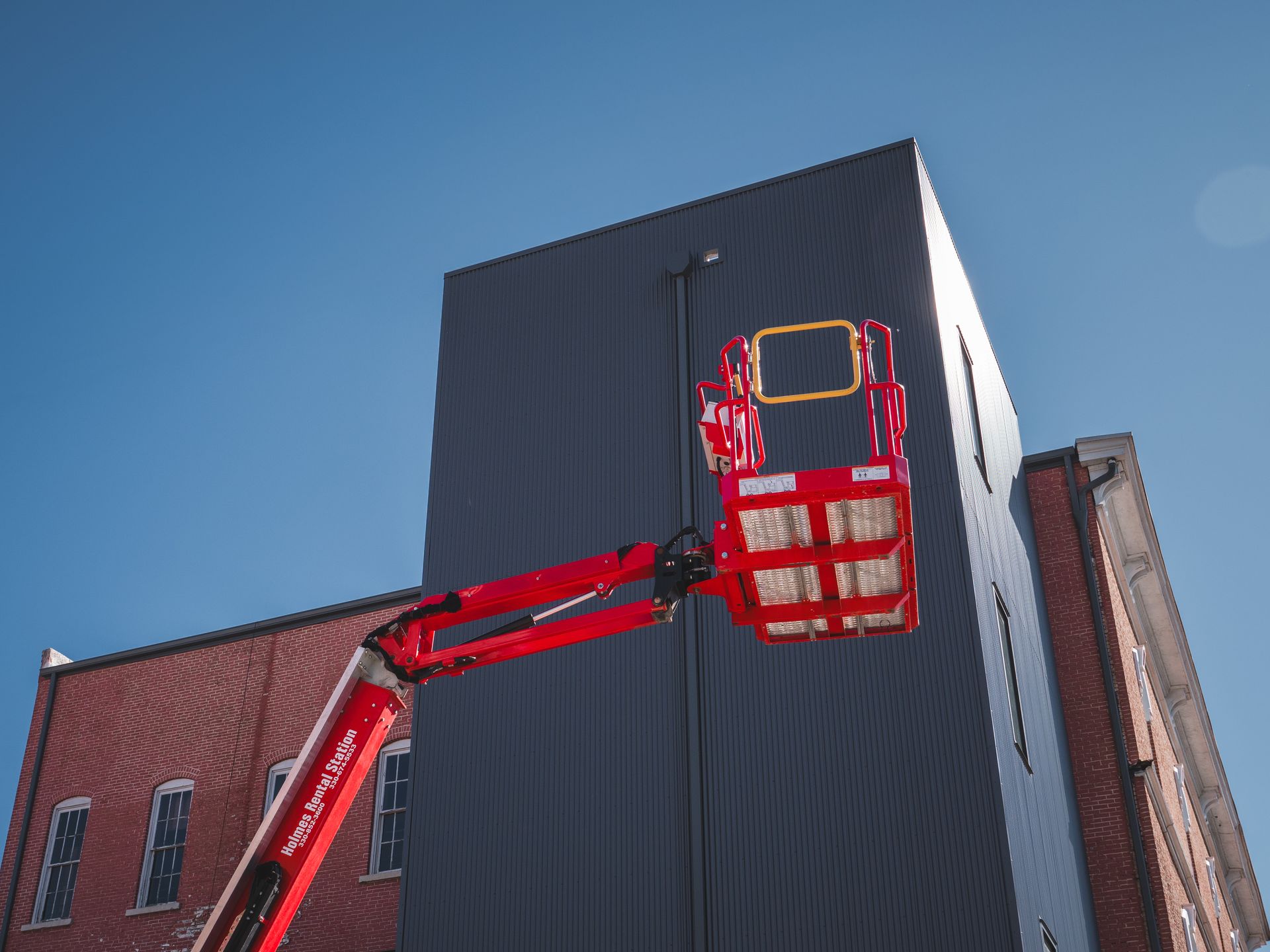 A red crane with a bucket on it is working on a building