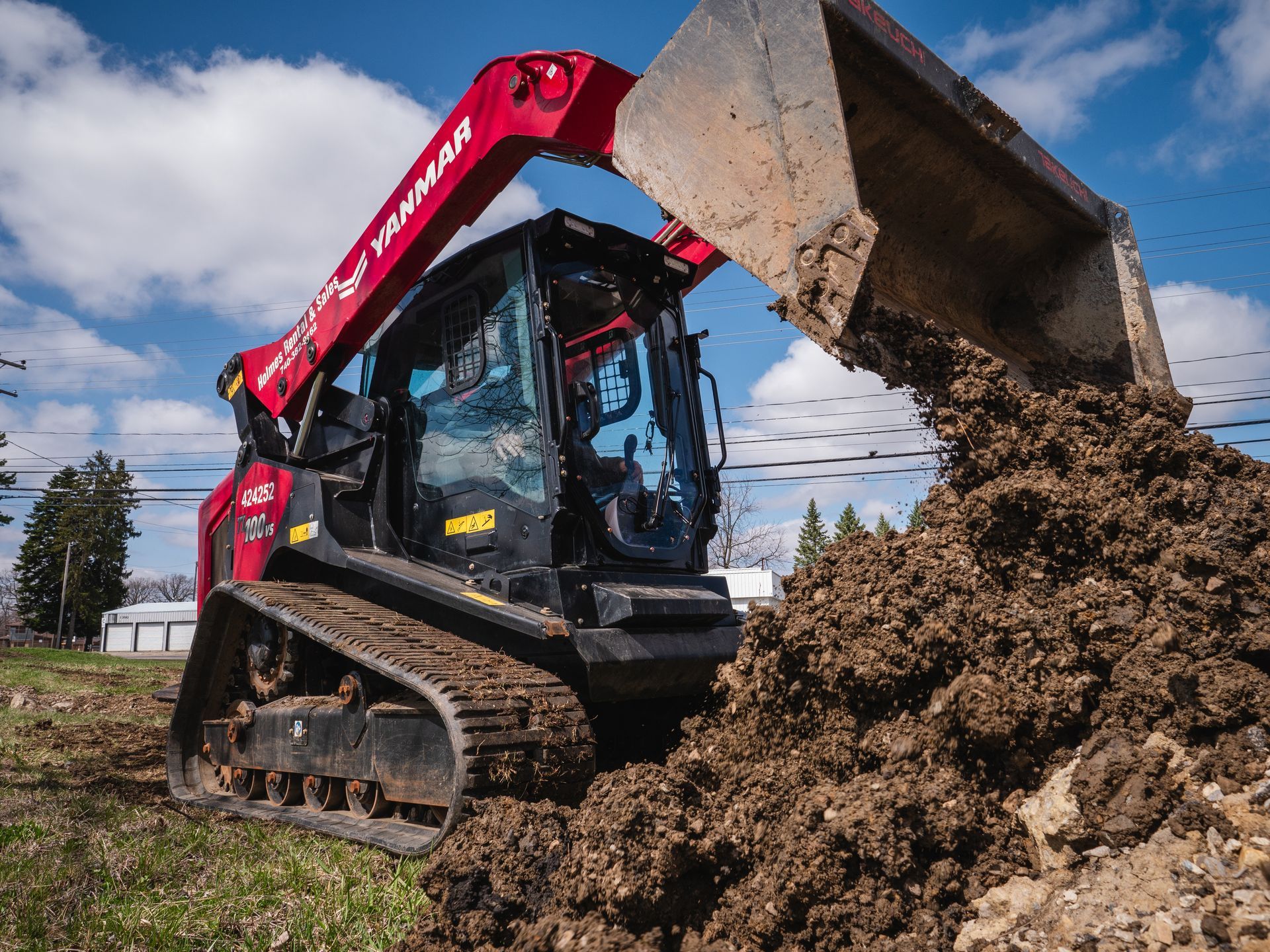 A bulldozer is loading dirt into a large bucket.