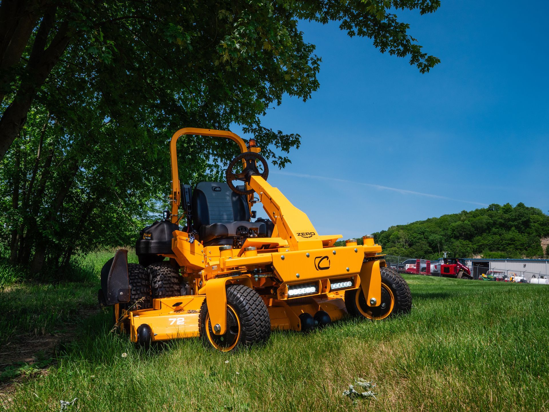 A yellow lawn mower is parked in a grassy field.