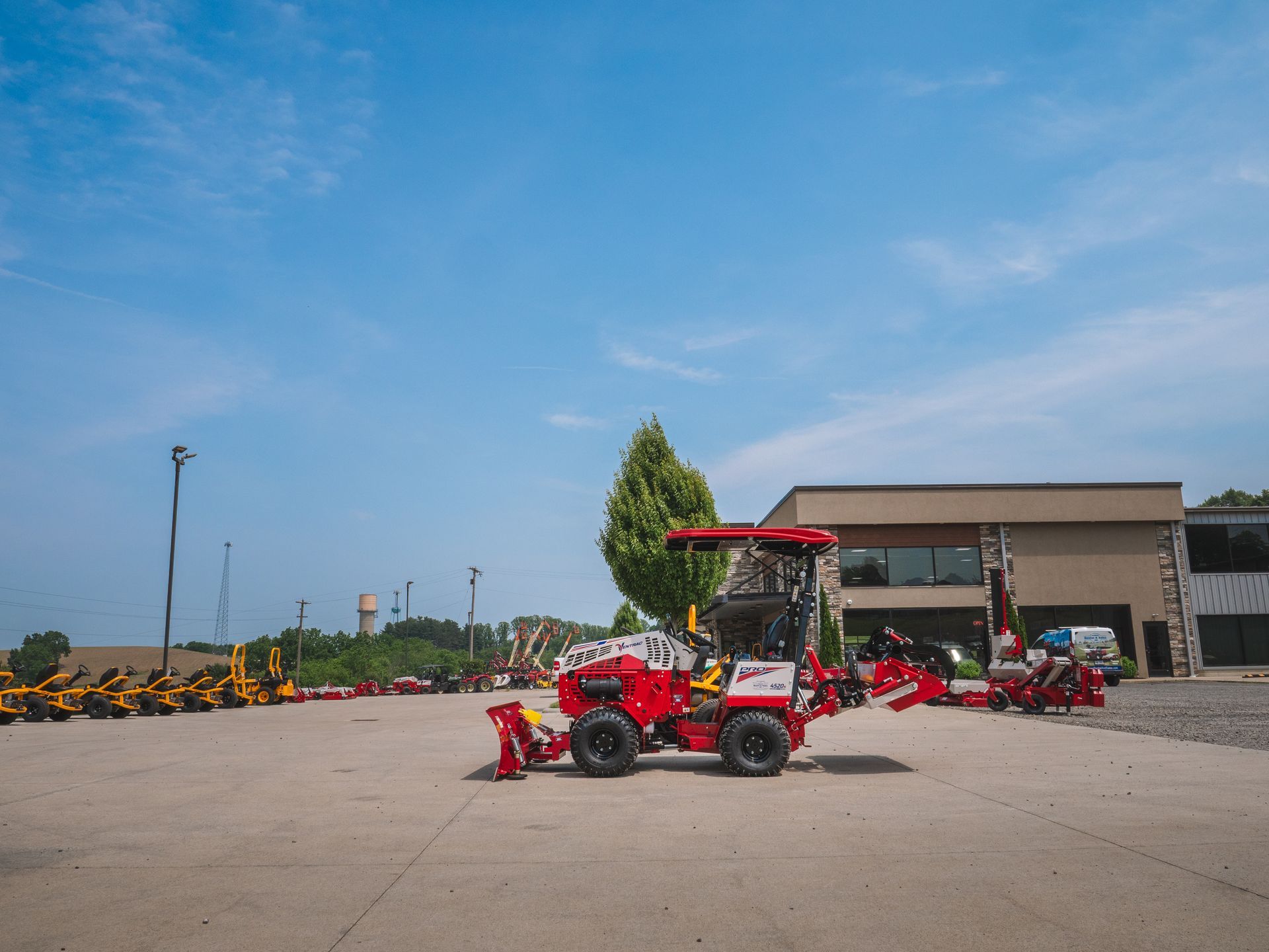 A red tractor is parked in a parking lot in front of a building.