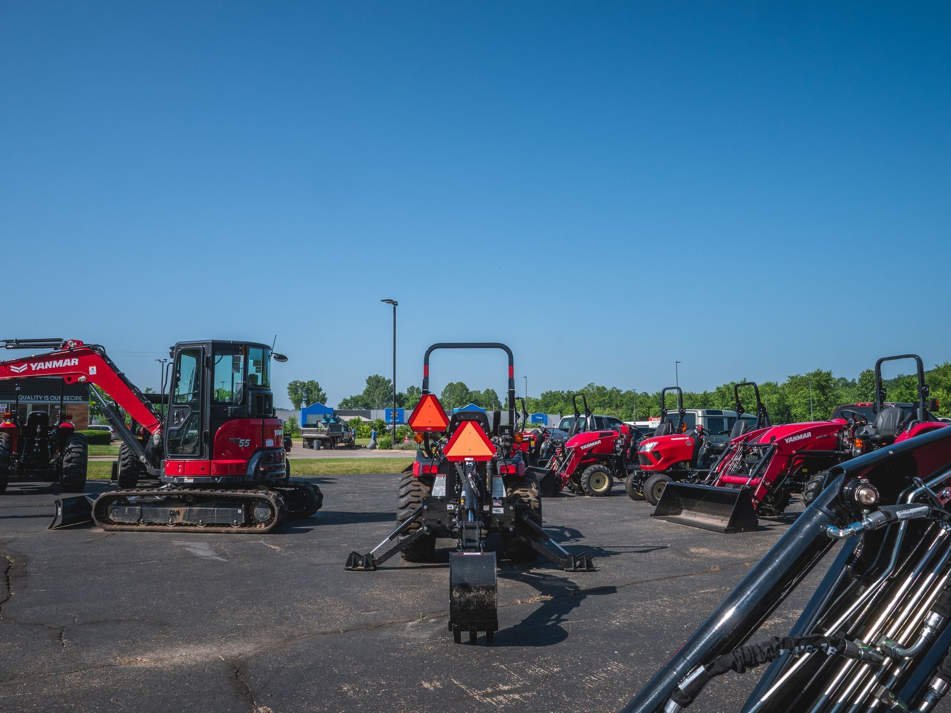 A row of red tractors are parked in a parking lot.