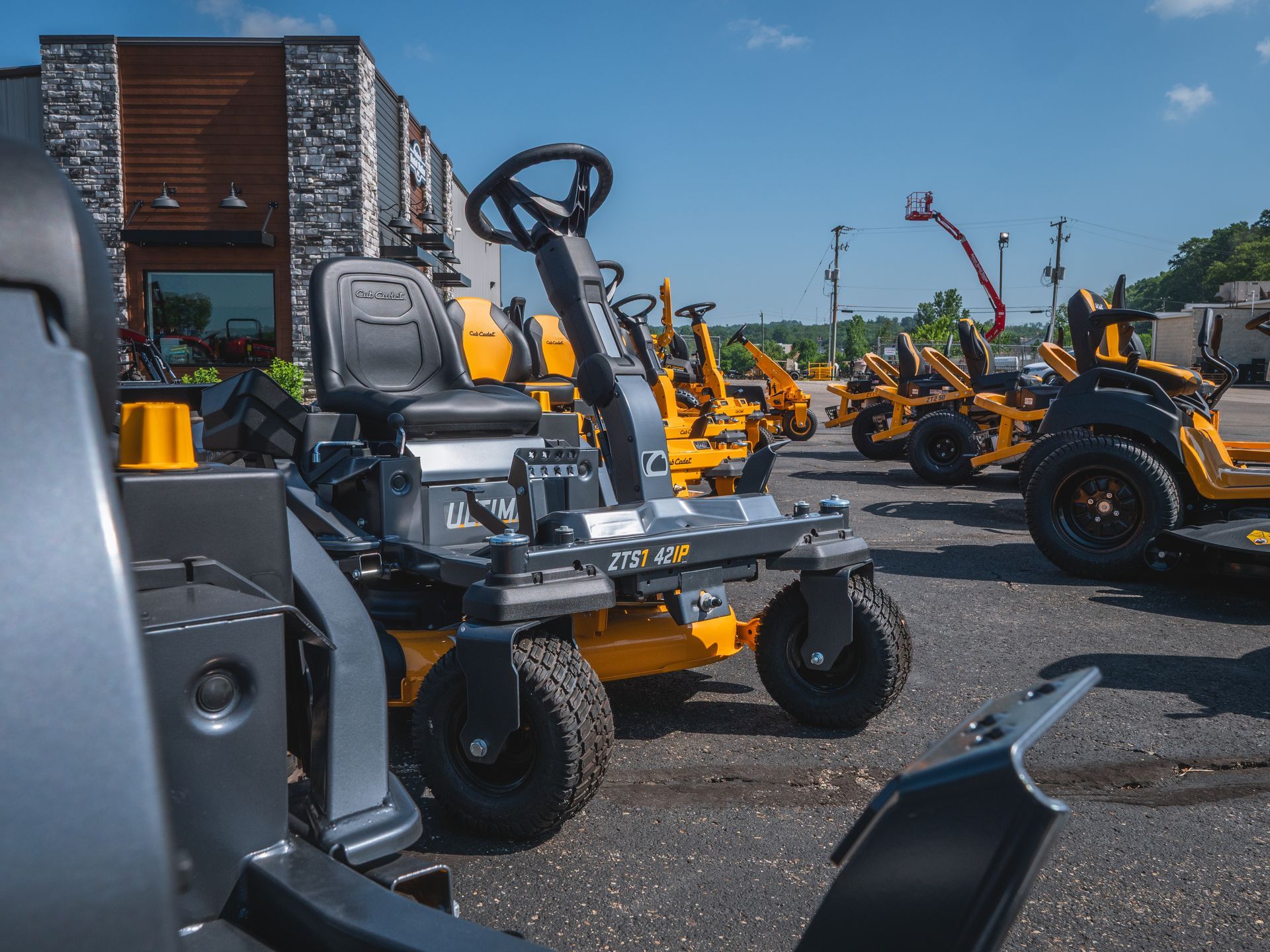 A row of lawn mowers are parked in front of a building.