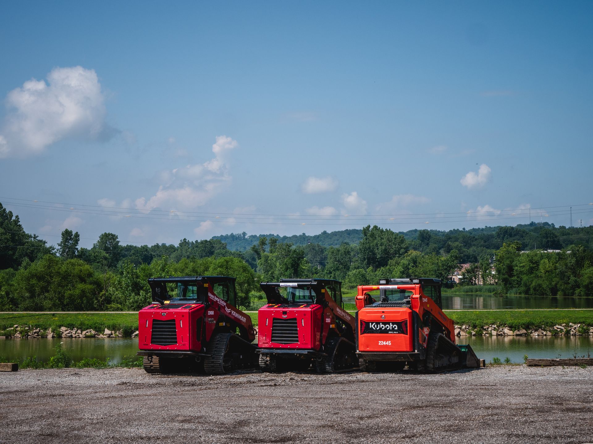 Two red tractors are parked next to each other in a dirt field.