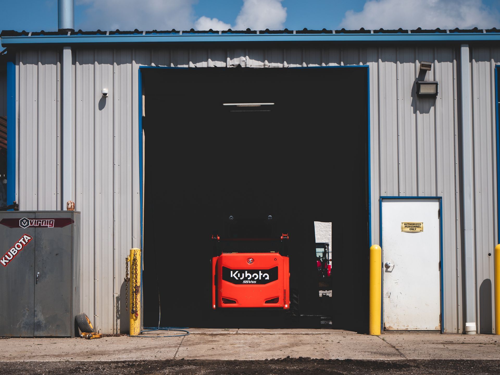 A kubota tractor is parked in front of a garage door.
