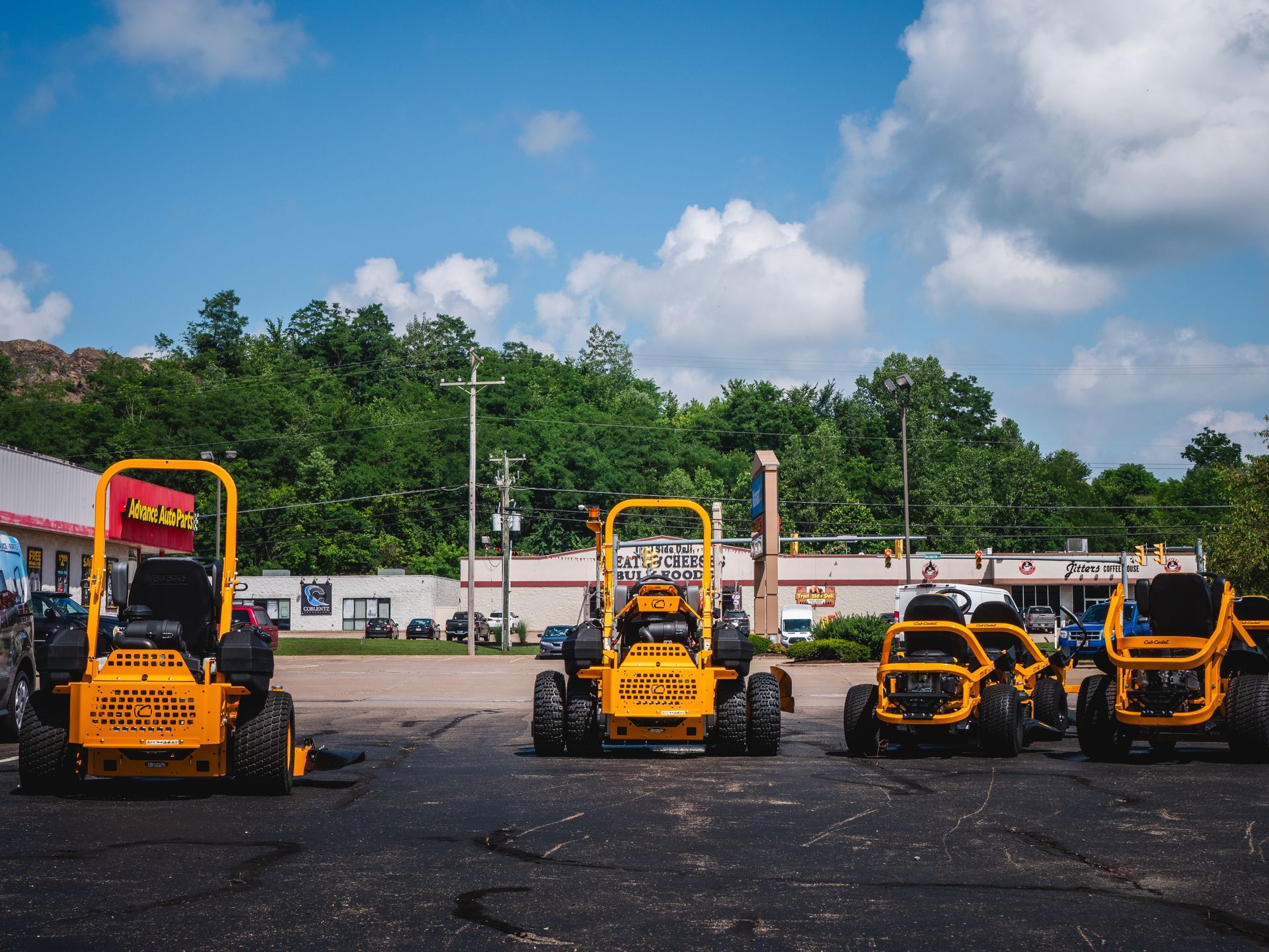 A row of yellow lawn mowers are parked in a parking lot.
