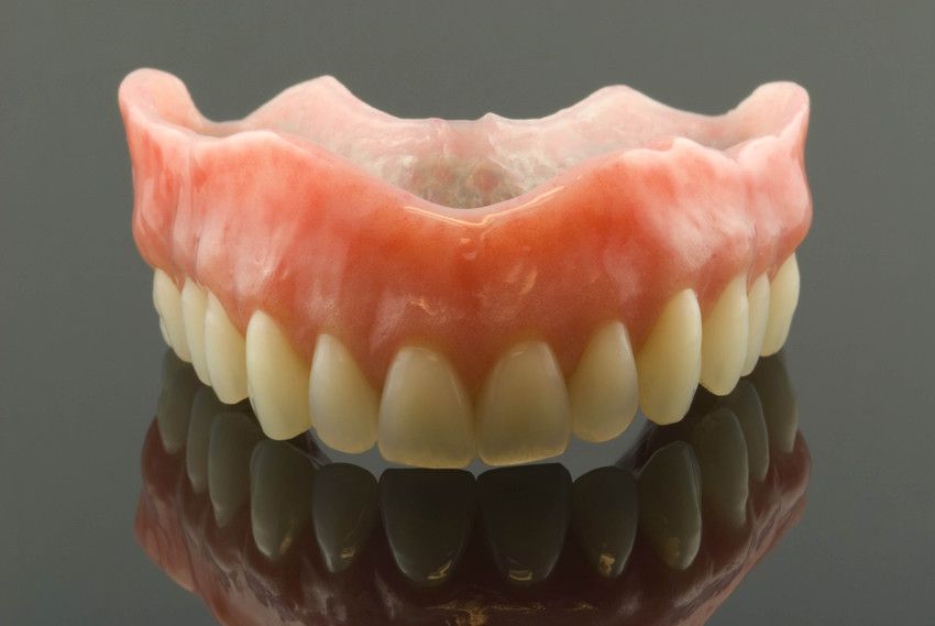 A full denture is sitting on a black surface.