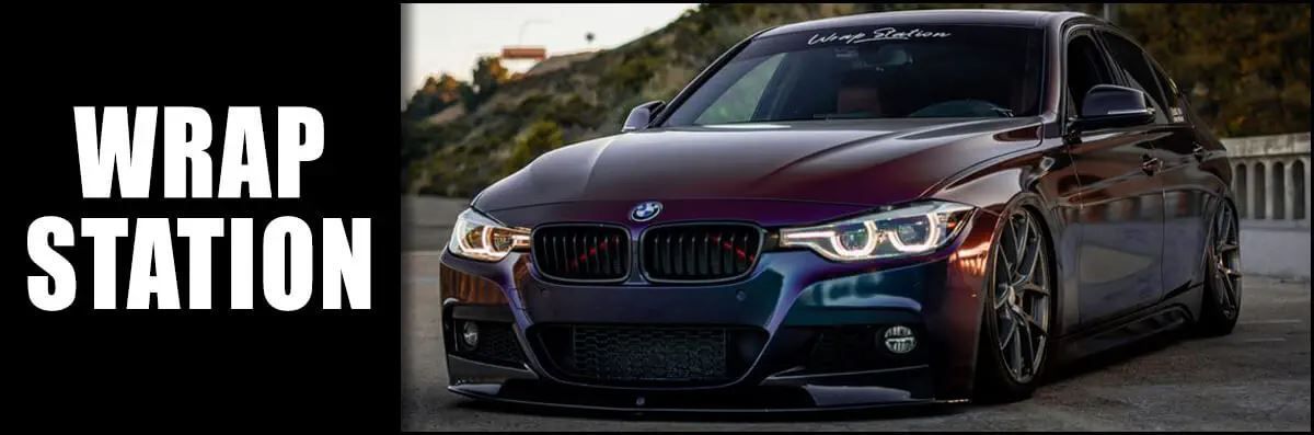 A bmw is parked on the side of the road next to a sign that says wrap station.