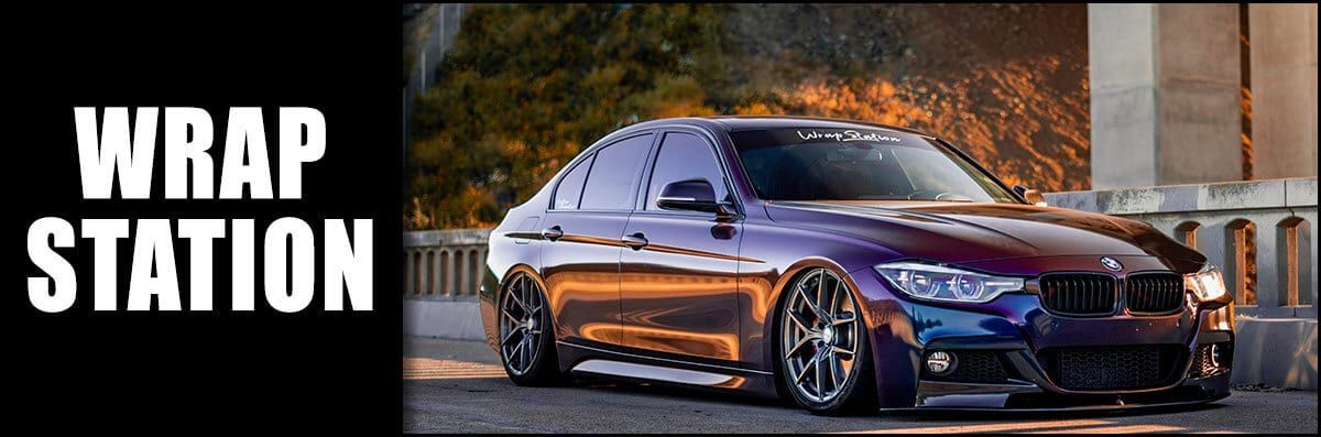 A purple car is parked in front of a building next to a sign that says wrap station.