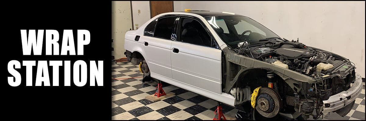 A white car is sitting on a checkered floor in a garage.