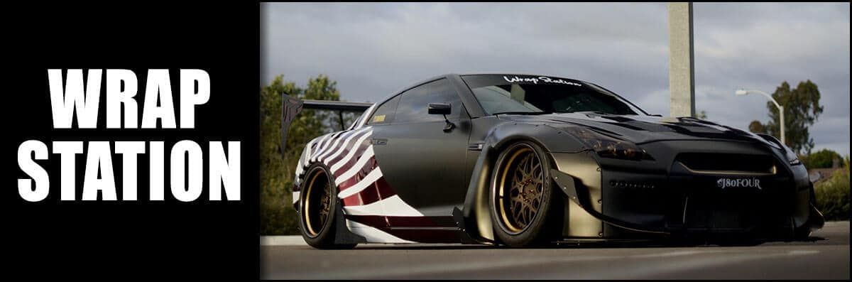 A black car is parked next to a sign that says wrap station