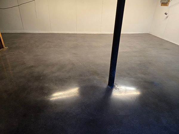 Empty room with a glossy gray floor and a blue support pole in the center