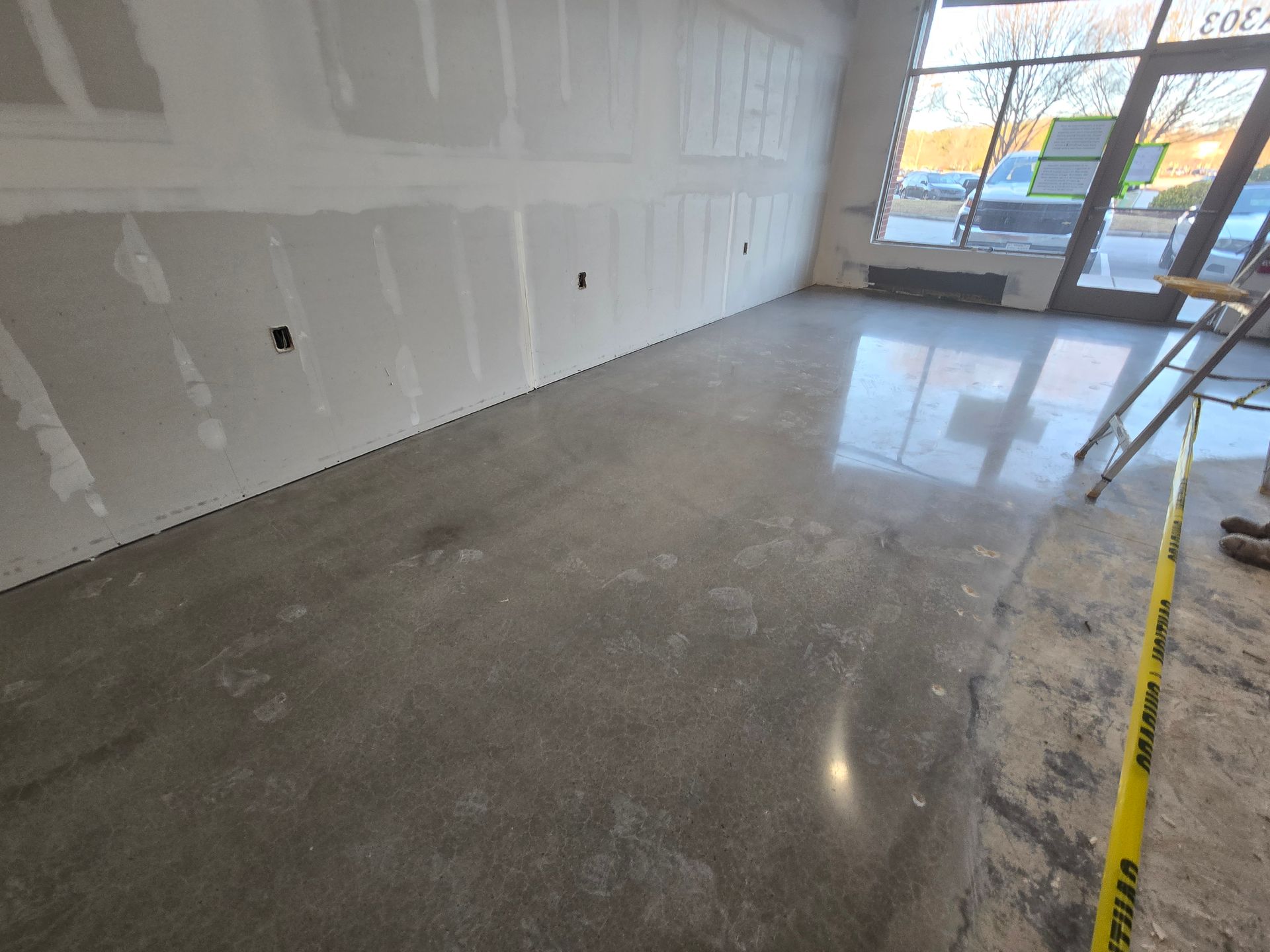 Empty room with concrete floor, unfinished drywall walls, and glass door.