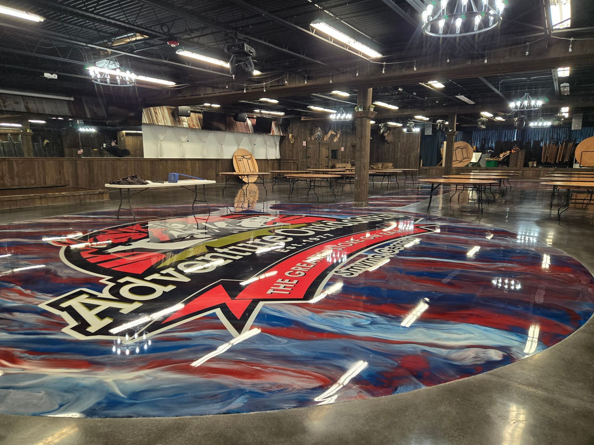 Large event space with epoxy floor featuring a colorful logo