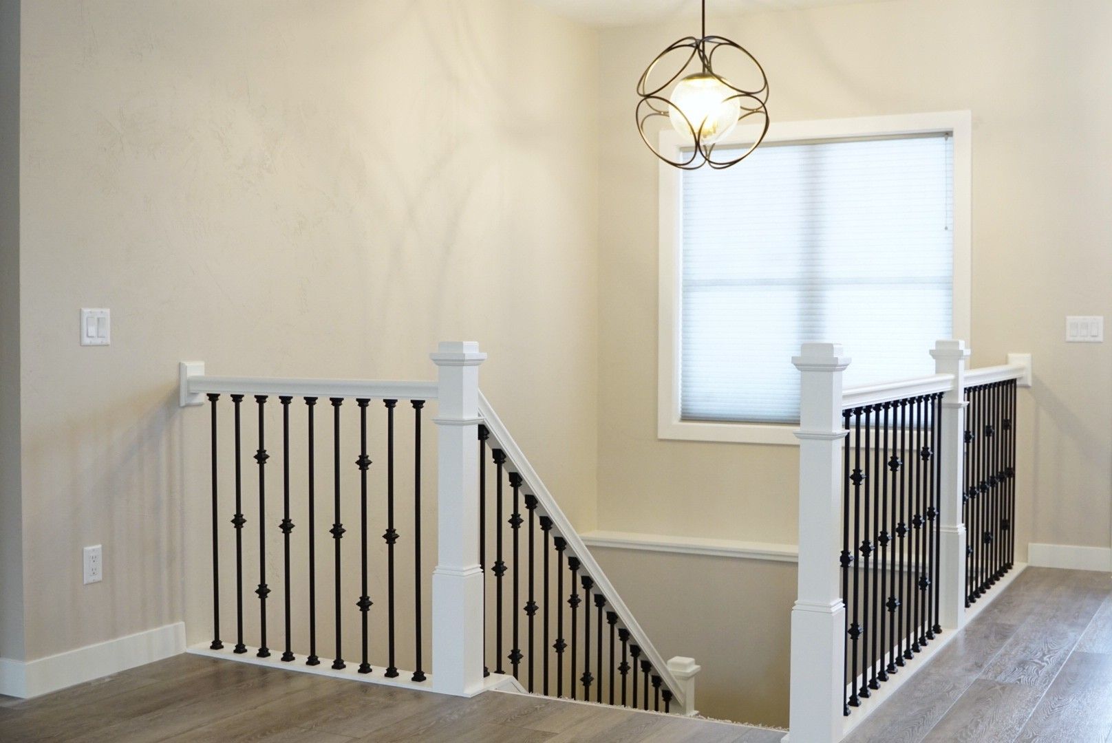 Bright stair landing with light walls, white railings, and black balusters.