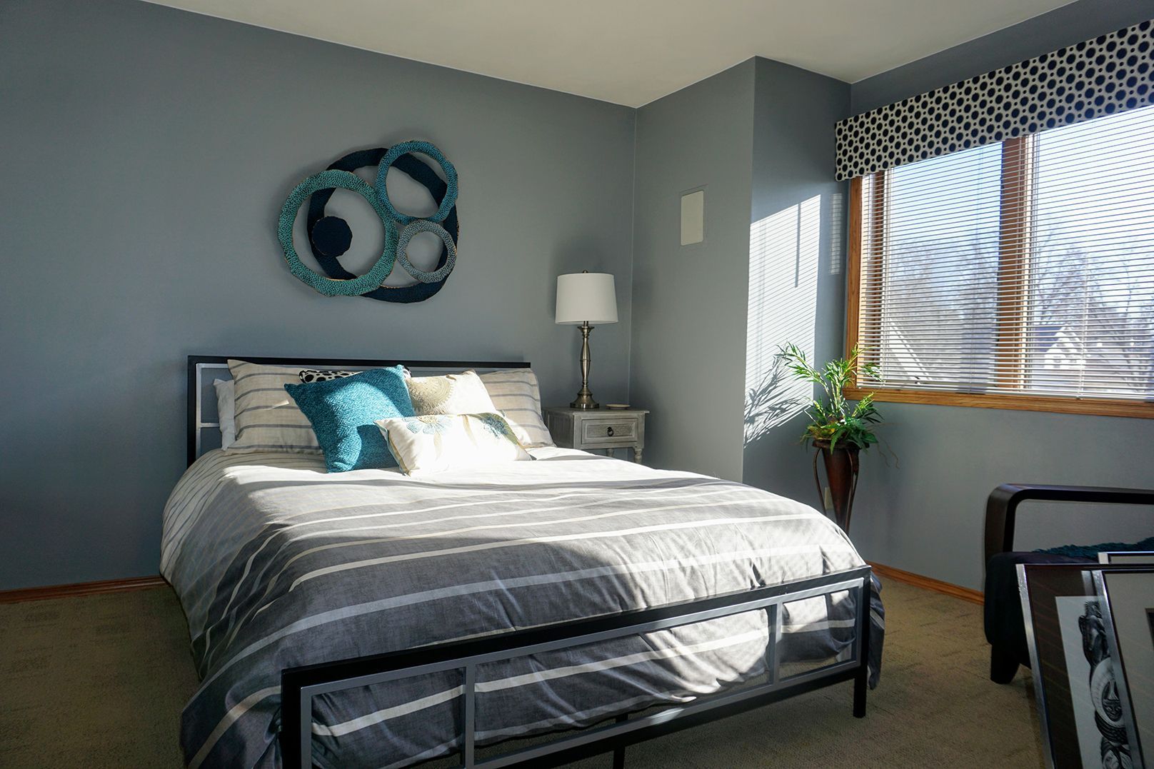 Bedroom with blue-gray walls and natural wood window trim.