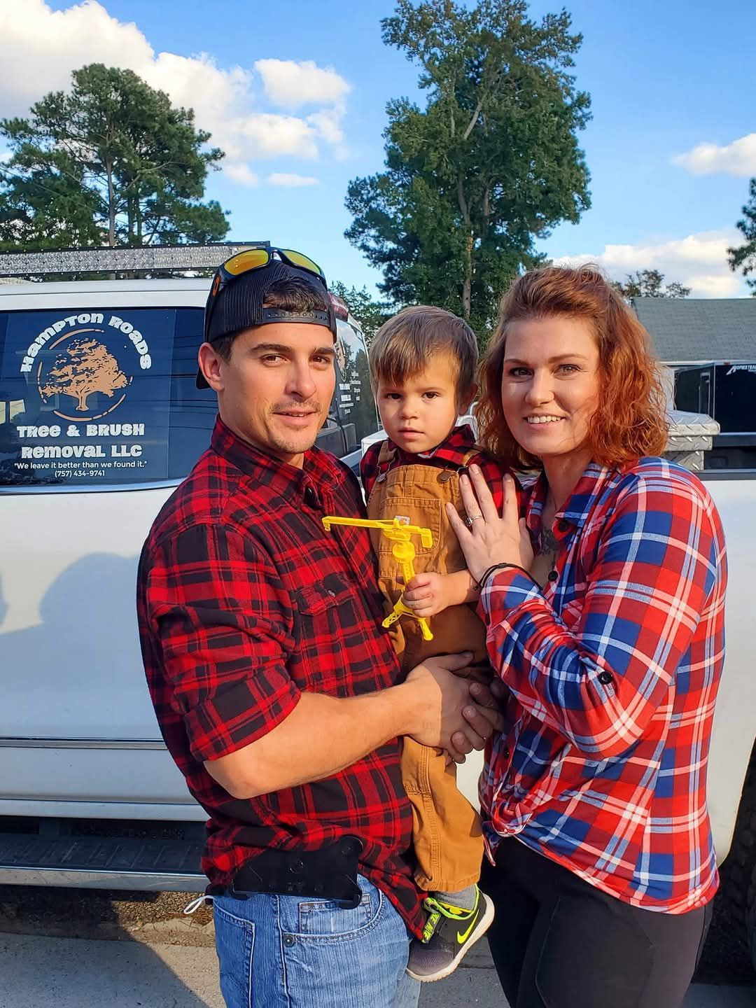A man and a woman are holding a baby in front of a truck.