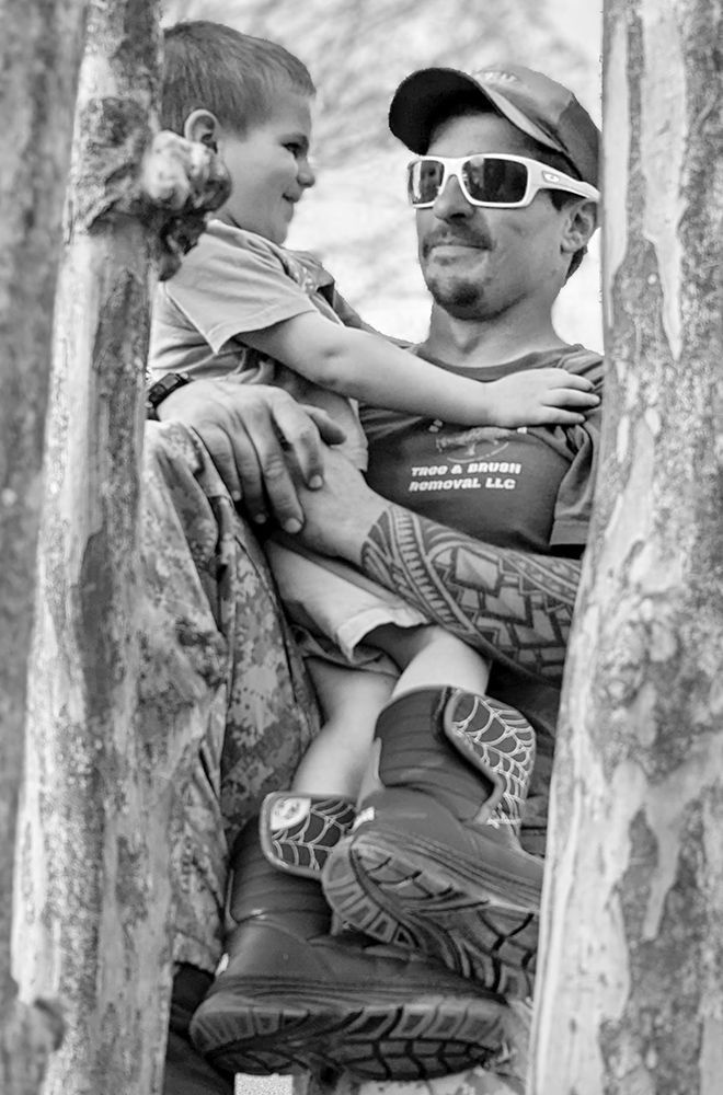 A man is holding a little boy in his arms in a black and white photo.