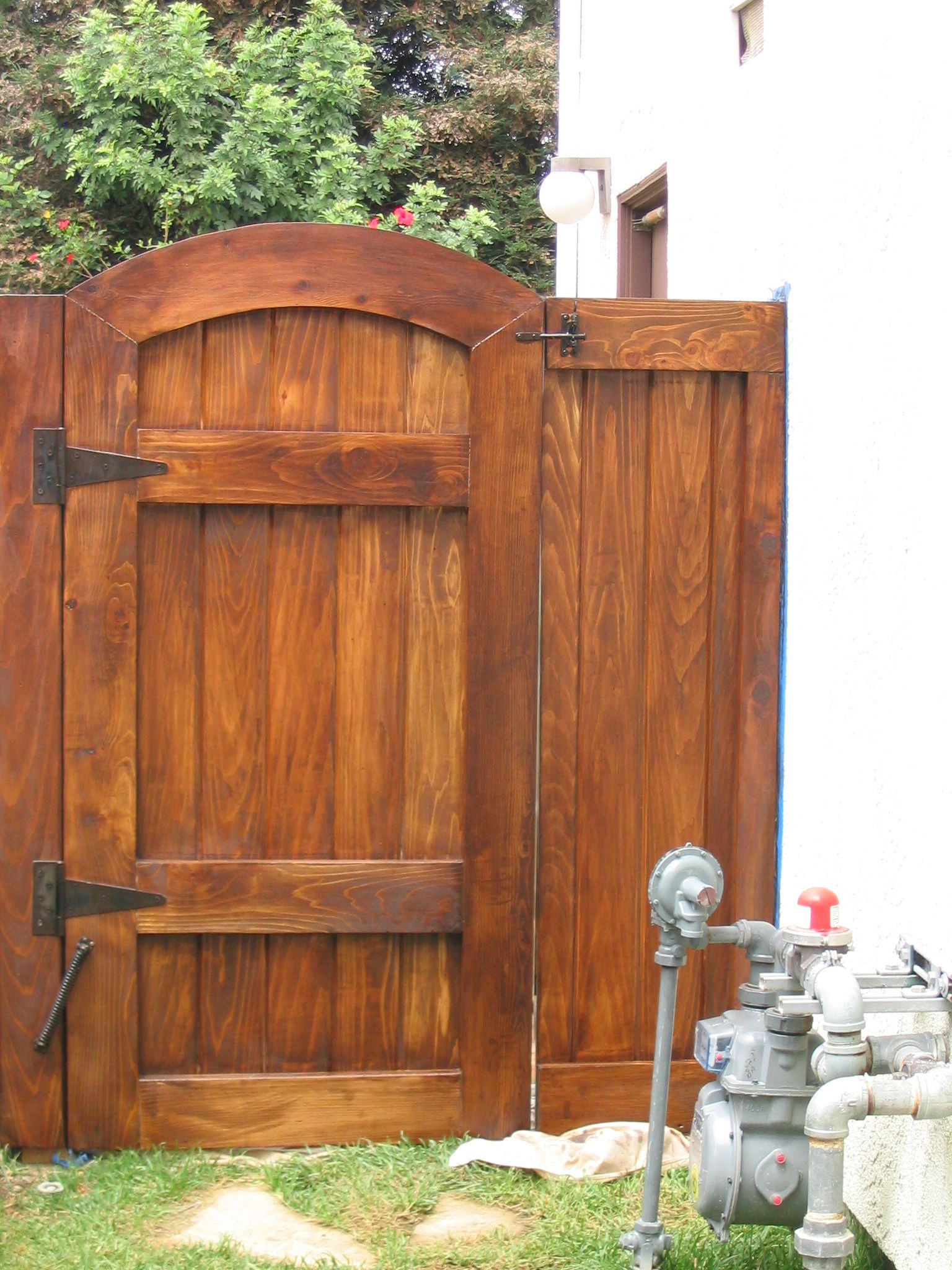 Wooden gate beside a white building, with gas meters in the foreground.