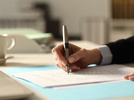 A person is writing on a piece of paper with a pen.