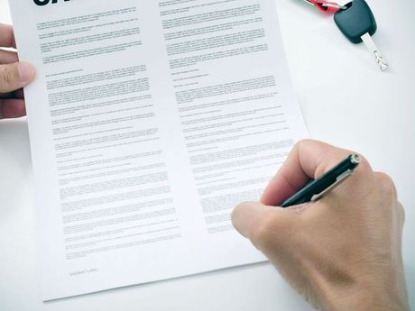 A person is writing on a piece of paper with a pen.