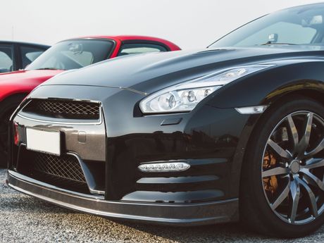 A black sports car is parked next to a red sports car.