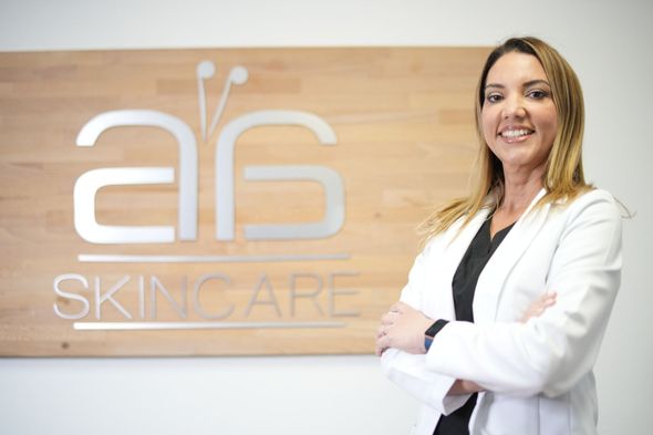 A woman in a white coat is standing in front of a sign that says skincare.